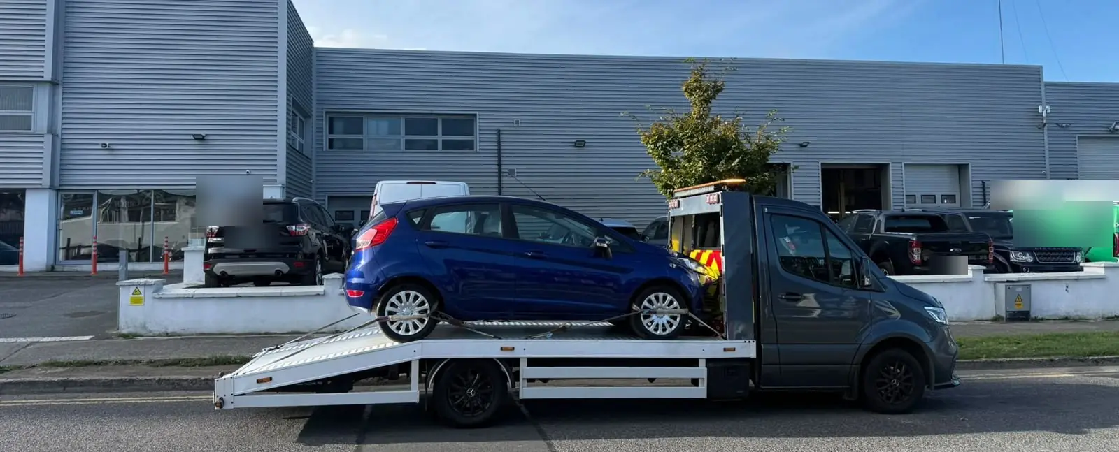 Our grey truck on a Dublin business park road, a blue hatchback on the back